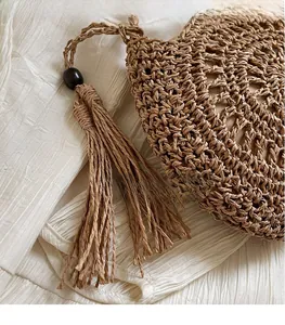 Detailed macro view of woven brown straw bag with stylish tassel and decorative bead