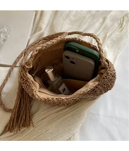 Detail of woven straw bucket bag interior showing spacious capacity for two phones and perfume