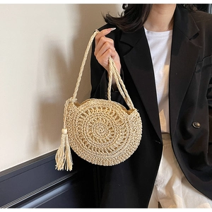 Detailed close-up of ivory hand-woven straw bag with radial texture and fringe tassel