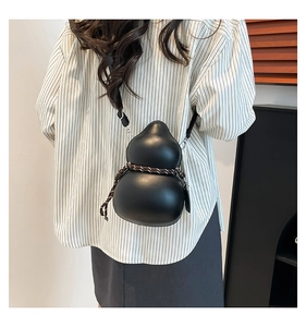 Detail of black gourd-shaped crossbody bag with woven rope trim worn by a model