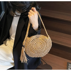 Macro detail of hand-woven straw bag featuring spiral hollow patterns and stylish tassels