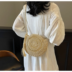 Detail of hand-woven straw crossbody bag with tassels and delicate hollow-out craft