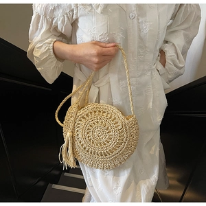 Close-up of hand-woven round straw bag with decorative tassel for beach vacations