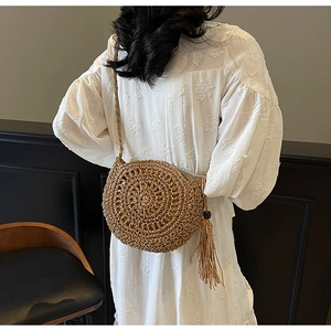 Detail of round straw bag showing radial weaving texture and long decorative tassels