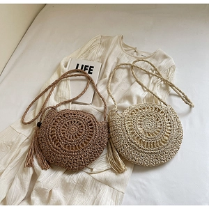 Detailed close-up of handmade round straw bags in coffee and beige with tassel charms