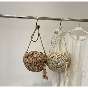 Detailed macro view of handmade straw woven round bags with elegant tassel and wood bead charm
