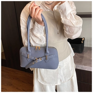 Detailed close-up of blue textured woven handbag with golden double zippers and buckles