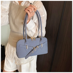 Close-up of violet textured shoulder bag featuring golden zippers and buckle strap detail