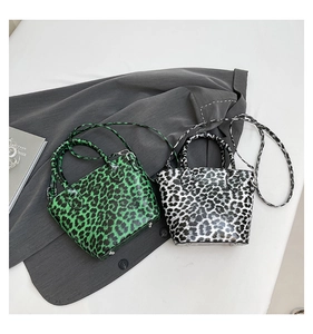Detail of glossy leopard print tote bags in green and white with metal studs
