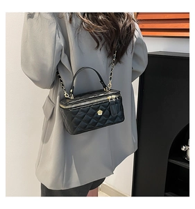 Close-up of quilted leather crossbody bag with gold floral buckle and chain strap
