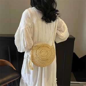 Handwoven straw shoulder bag for summer beach fashion with round design and side tassels