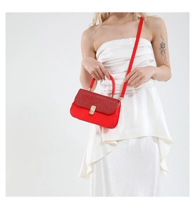 Détail du rabat à paillettes rouges sur un sac bandoulière avec boucle métallique dorée