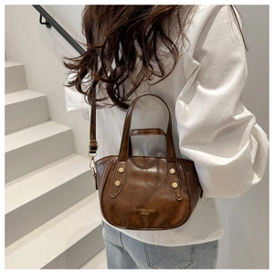 Vue détaillée d'un sac à main vintage marron foncé en cuir avec des clous dorés