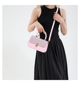 Detailed view of pink textured flap shoulder bag with gold square buckle and adjustable strap