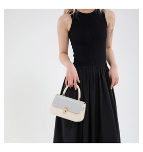 Detail of crossbody bag with cream leather finish, silver glitter flap, and gold twist lock