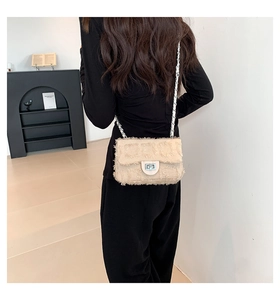 Close-up of beige textured crossbody bag with silver chain and fringe detailing