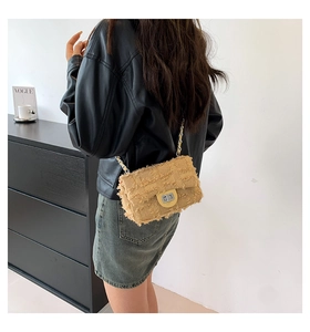 Detail of yellow frayed canvas crossbody bag with silver chain strap and turn-lock