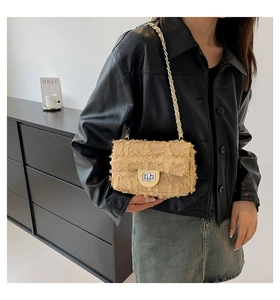 Gros plan sur un sac bandoulière en tweed beige avec bords effilochés et chaîne