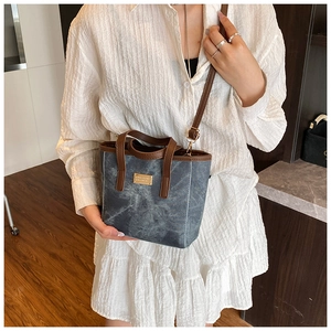 Detail der blauen strukturierte Tote Bag mit braunen Ledergriffen und Goldplakette