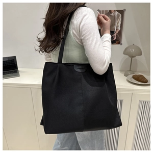 Close-up of black canvas tote bag with a leather fashion patch on the front surface