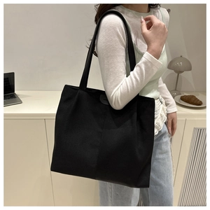 Detail shot of a minimalist large capacity black nylon tote bag styled for daily commute