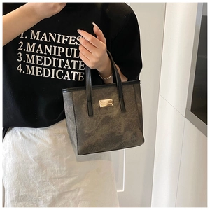 Detailaufnahme der Vintage-Tote-Bag mit Distressed-Textur und goldener Metallplakette