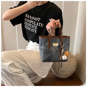 Details der Vintage-Tasche aus gewaschenem Denim mit Ledergriffen und Baseball-Anhänger