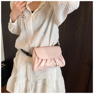 Close-up of pink pleated crossbody bag featuring metal chain strap and silver ball detail