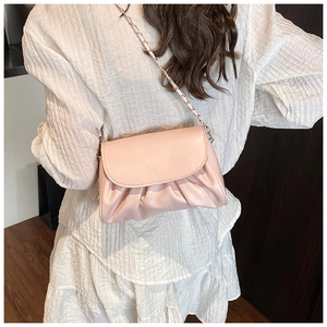 Detail of pink pleated cloud bag with silver chain strap worn with white dress