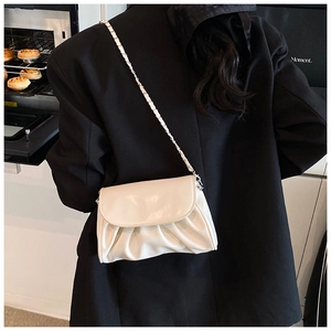 Chic cream white ruched handbag with metal chain strap shown against black suit