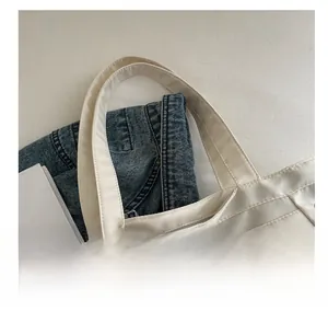 Detail of white nylon tote strap stitching and sporty tennis racket metal charm
