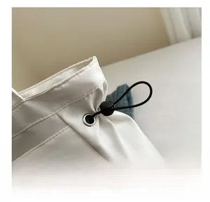 Close-up of white tote bag showing nylon fabric, elastic drawstring and silver metal eyelets