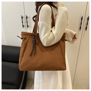 Detail view of large brown nylon tote bag with side drawstring and decorative lanyard