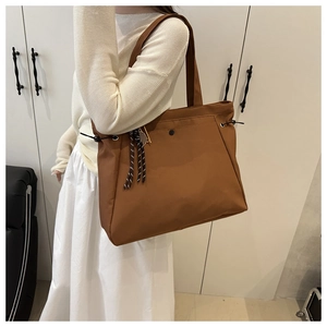 Detailed view of a brown large capacity tote bag with side drawstring and tassel detail