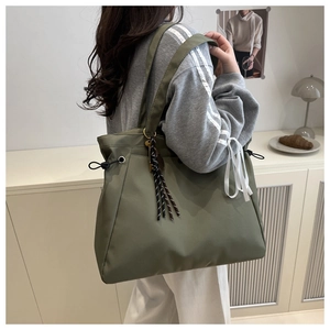 Detailed side view of an olive green nylon tote bag with drawstring and shoulder strap