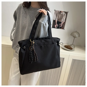 Close-up of black nylon tote bag with drawstring details and striped knot ornament