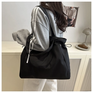 Close-up of black nylon tote bag with drawstring closure and metal eyelet details