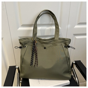 Detailed view of an olive green nylon tote bag featuring magnetic buckle and woven tassels
