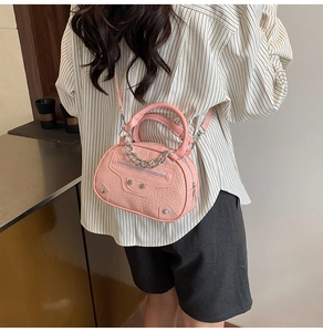 Detail view of pink croc-embossed round handbag with silver studs and chain strap