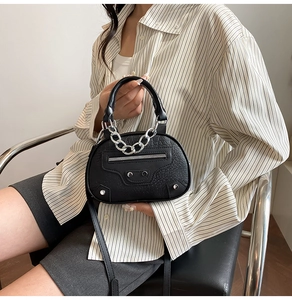 Detail of black crocodile texture leather bag with motorcycle style silver metal chain