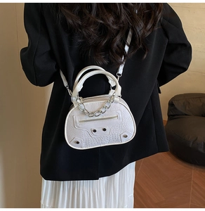 Detail of white crocodile pattern shell bag with silver chain and rivet accents