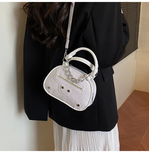 Detail of white crocodile pattern bag with silver chain handle and motorcycle style studs