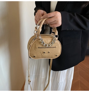 Detailed macro view of the beige faux-croc texture with silver studs and chain on the bag