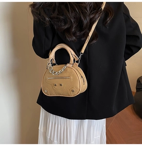 Detail of tan crocodile embossed mini bag with silver chain and rivet accents