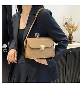 Chic camel leather crossbody bag with elegant gold metal clasp shown on model in studio