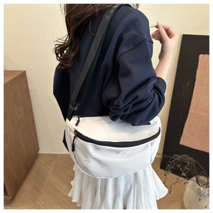 Detail of white nylon crescent crossbody bag with adjustable black strap on a model