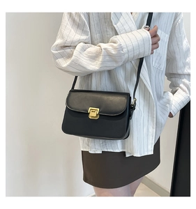 Chic black leather square crossbody bag with a gold metal lock worn by a model