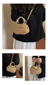 Dettaglio di una mini borsa beige effetto coccodrillo con borchie argentate e nappe