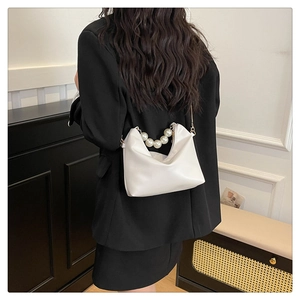 Detailed shot of white leather handbag with oversized pearl handle and gold metal hardware