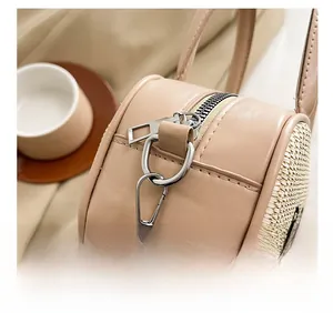 Detail of silver hardware and straw texture on beige bowling bag with leather accents
